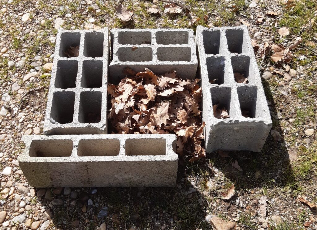 Quatre parpaings avec des feuilles mortes.