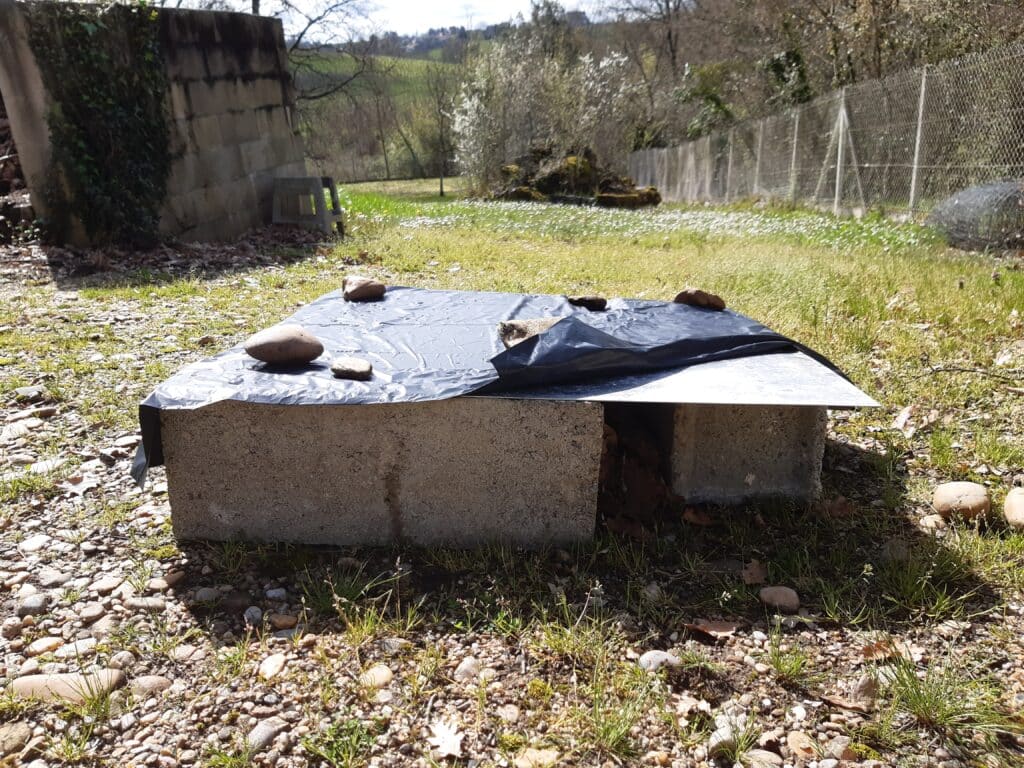 Maison pour hérisson: parpaings recouvert d'une plaque en fer et d'une bâche.