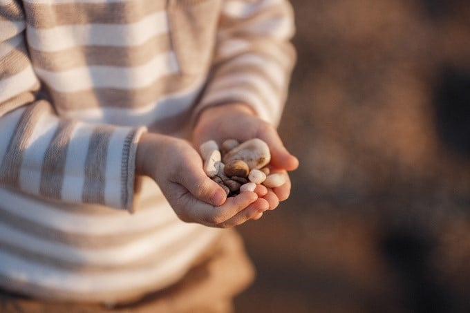 Un enfant tient dans ses mains des cailloux.