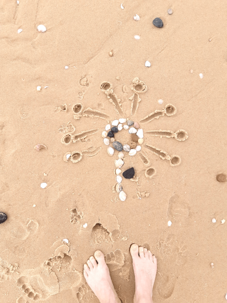Dessin dans le sable avec des coquillages et le doigt.