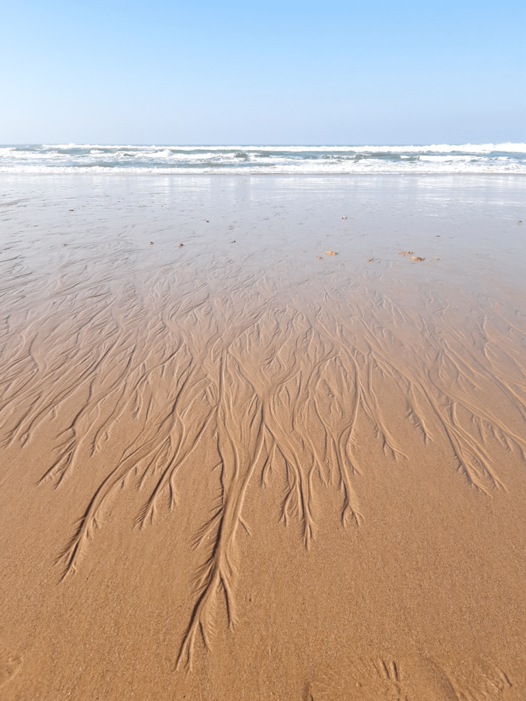 Dessin de l'eau qui se retire sur le sable en bord de mer.