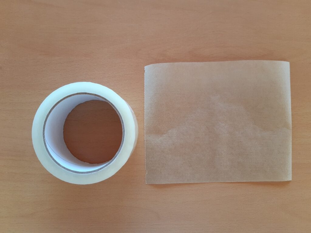 Feuille de papier cuisson avec rouleau de scotch sur une table en bois.