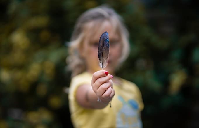 Une plume dans les mains d'une petite fille.