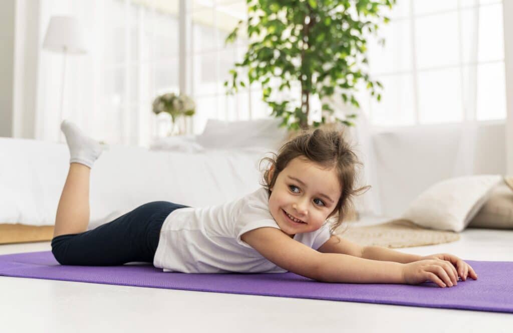 Petit fille qui fait de étirements sur un tapis de sol