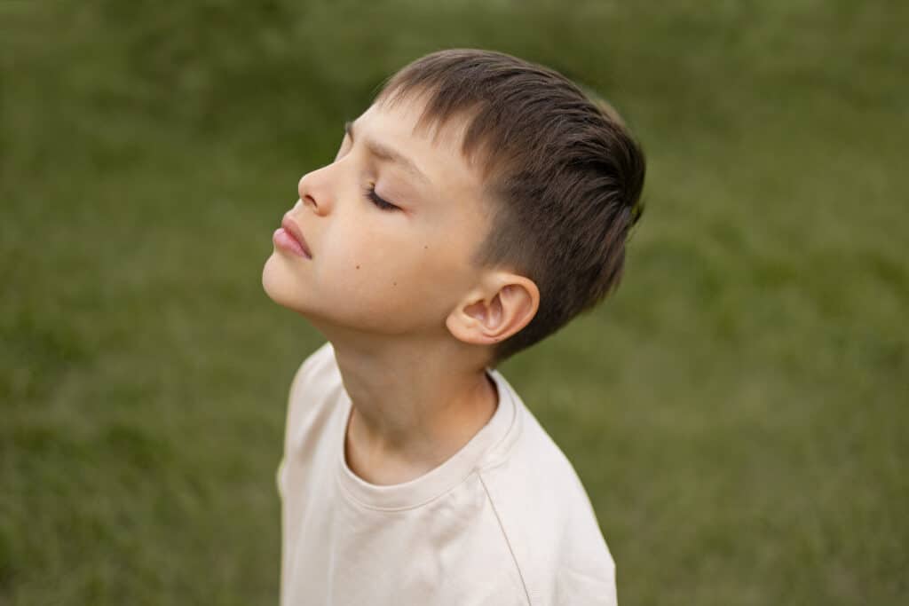 Enfant les yeux fermés qui respire dans la nature