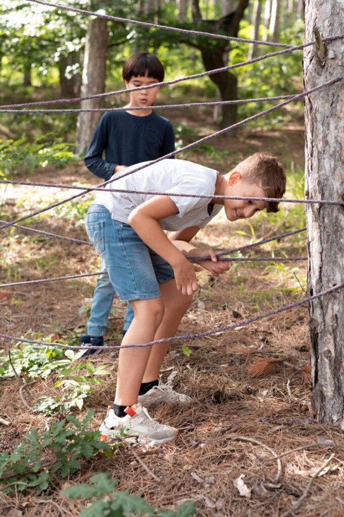 Deux enfants font un parcours d'agility avec des cordes autour d'arbres.