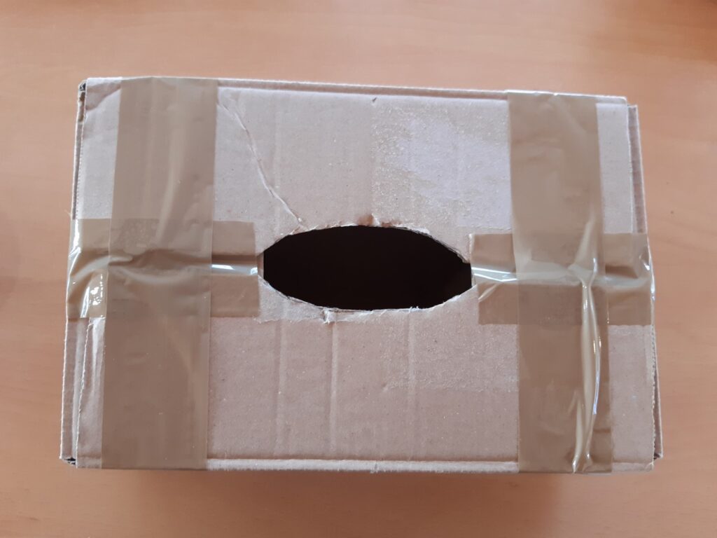 Boîte en carton avec une ouverture sur le dessus et scotchée.