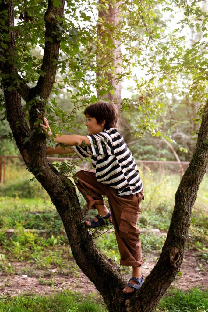 Un jeune garçon grimpe à un arbre.