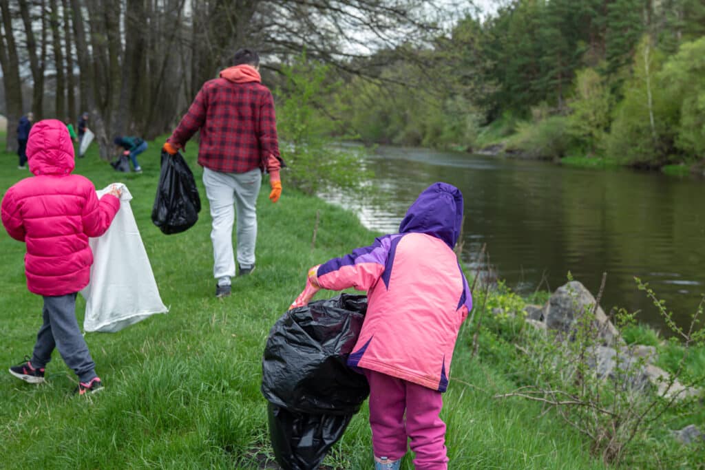 Nettoyage des bords de la rivière : un groupe de personnes dont des enfants nettoient la nature autour de la rivière.